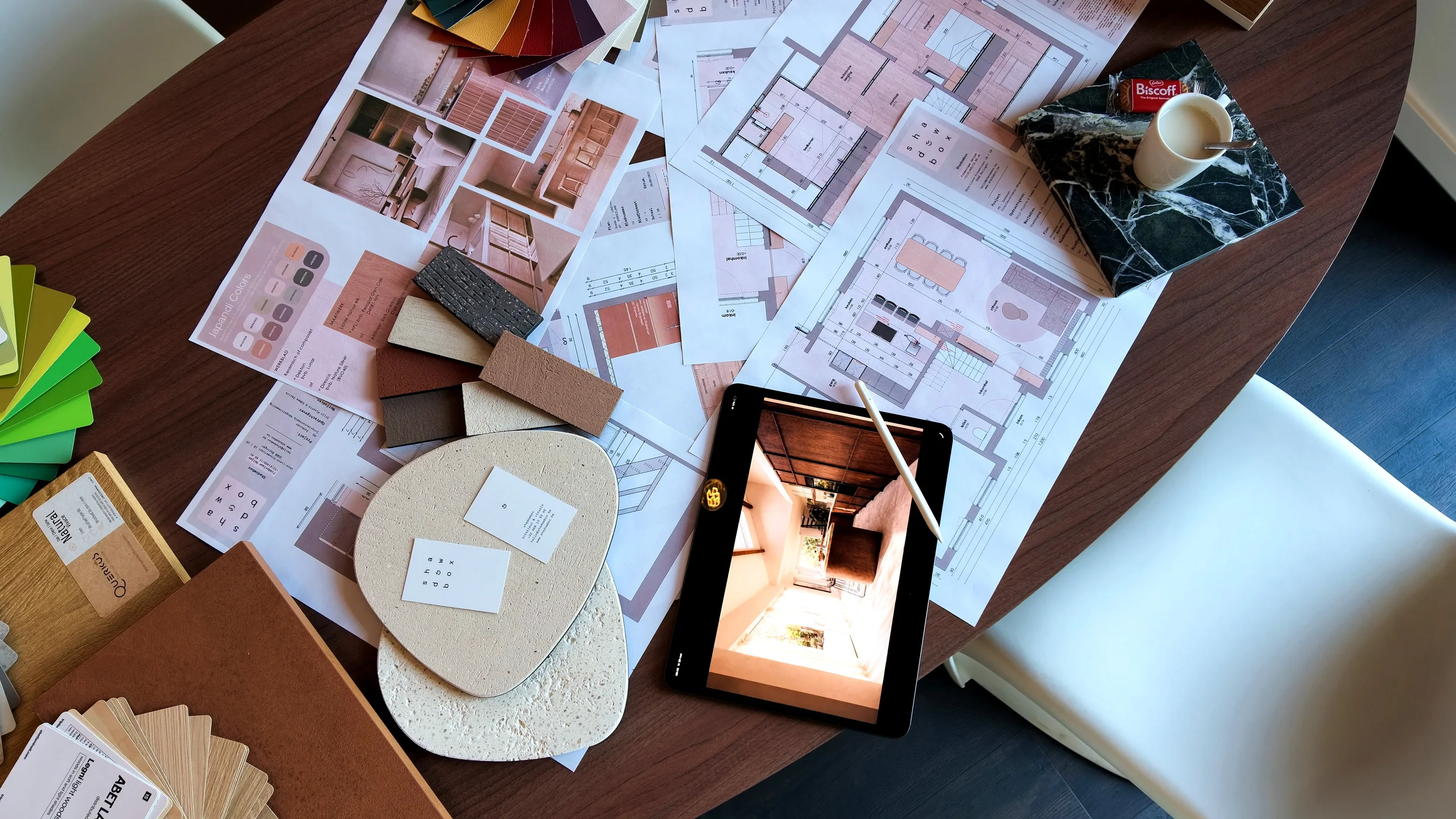 Plannen, materiaalstalen en een render op tablet op de ontwerptafel